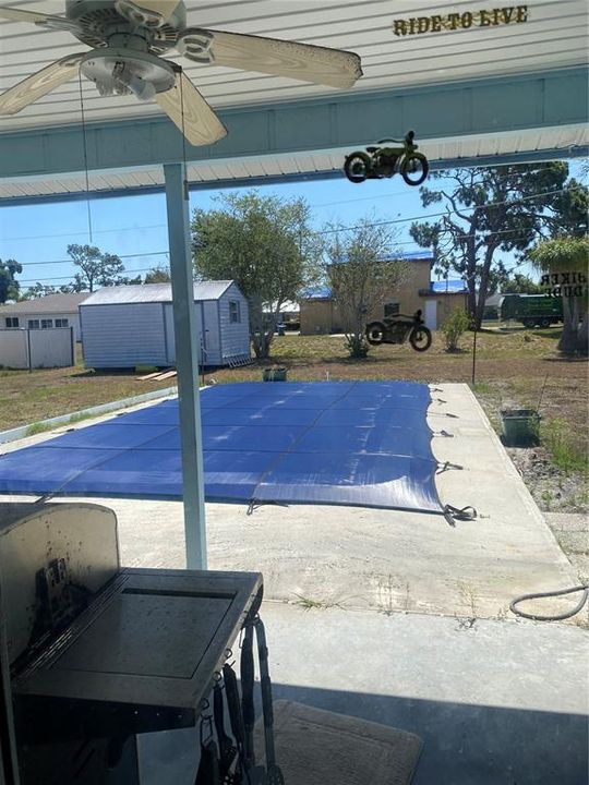 Standing in covered lanai looking at pool and large lot.