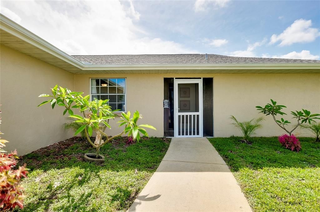 Front of the home with Plumeria plants.