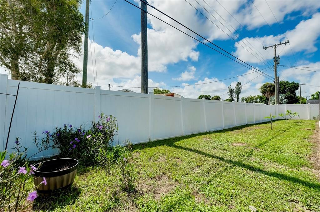 Open green space between pool cage and fence.