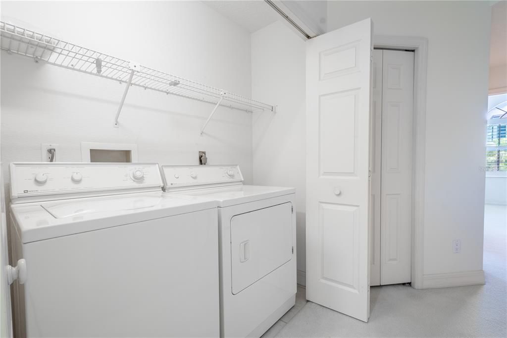 Upstairs hall closet features a washer/dryer with shelving above.