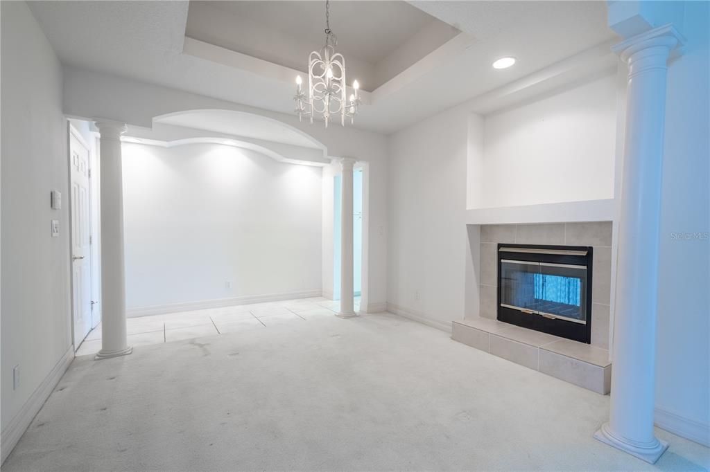 Formal dining room room featuring tray ceiling with chandelier and wood burning fireplace.