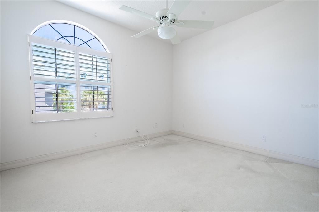 Bedroom 3 features a built-in closet, a ceiling fan with light kit, plantation shutters, and neutral tone walls and carpet.