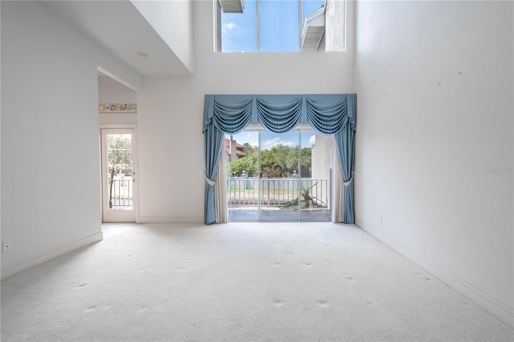 The 16' X  14' living room with 20’ ceiling has sliding glass doors leading to patio overlooking the pond