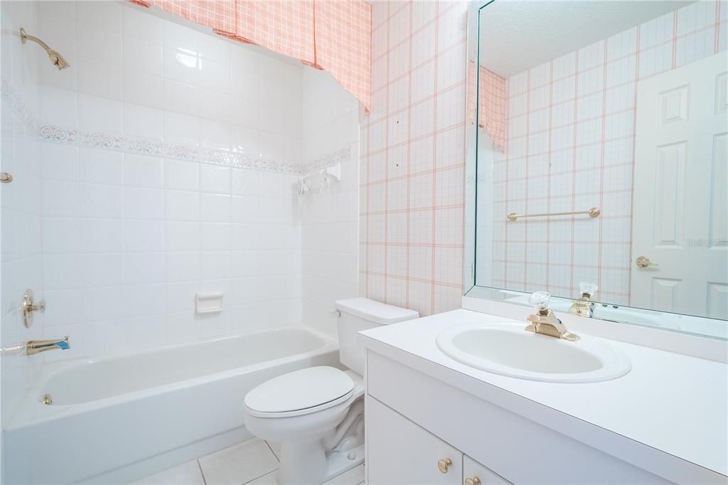 The 2nd Floor guest bath features a  mirrored vanity with storage, ceramic tile floor and a tub with shower.