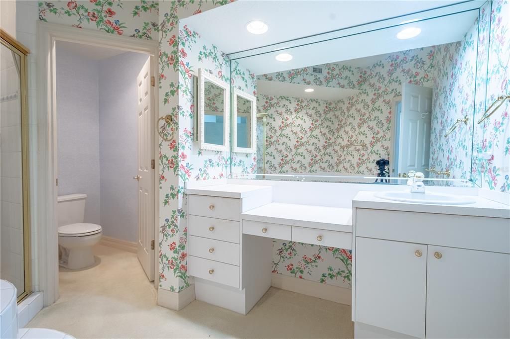 The primary ensuite features a mirrored vanity with storage, recessed lighting, and a make-up counter