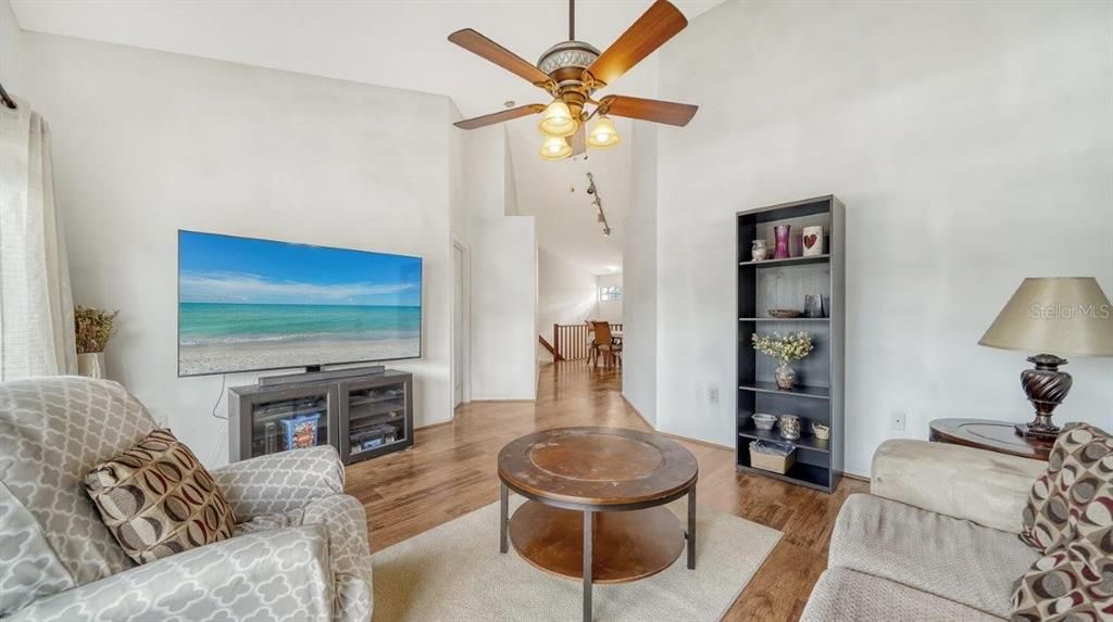 Living Room featuring laminate flooring, and sliding glass doors out to the covered lanai with views of the community pool.