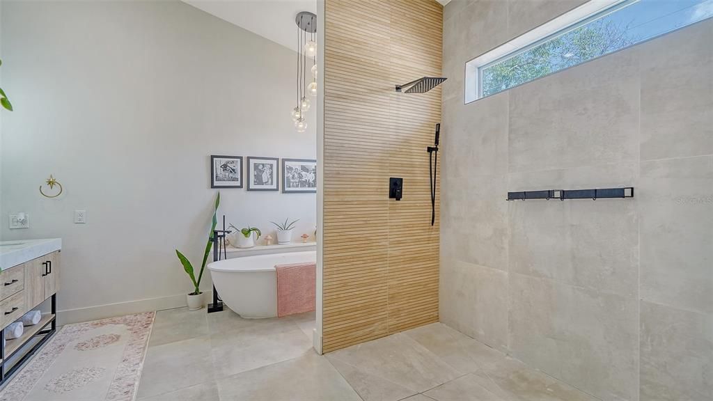 The Primary ((1st) Bathroom with walk-in shower, separate tub, and dual sinks.