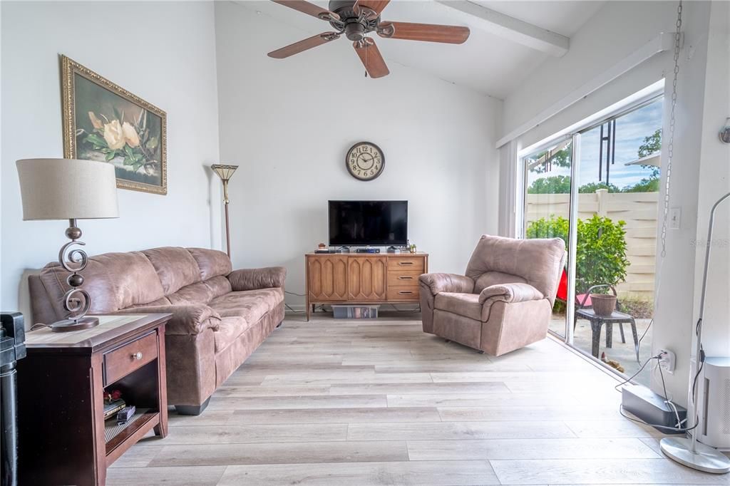 The living room features vaulted ceiling with ceiling fan, neutral tones and abundant natural light.