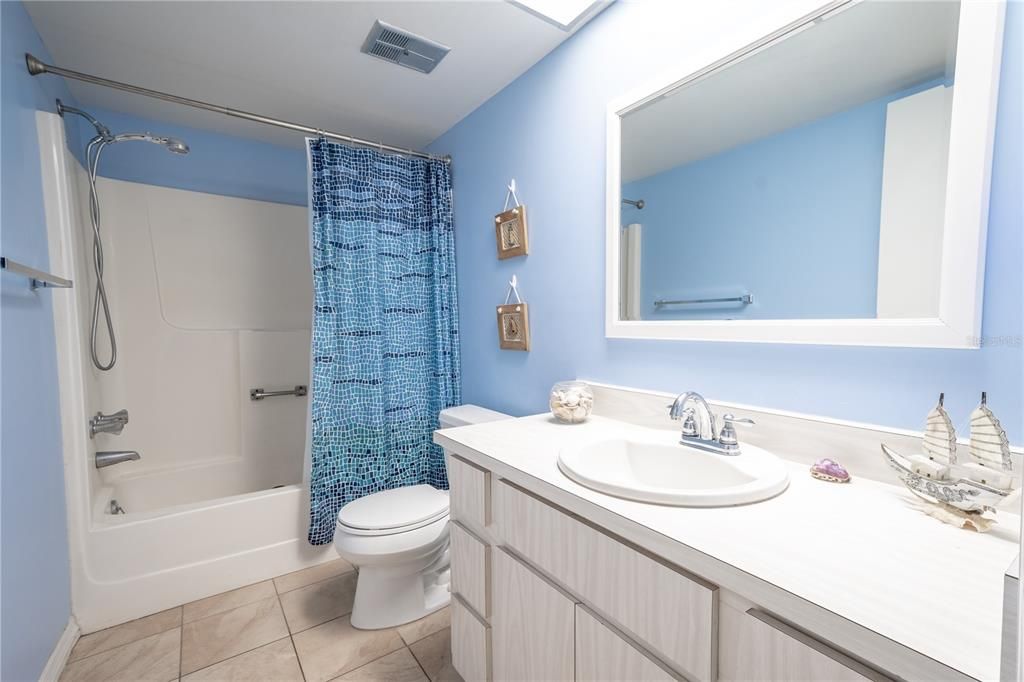 Bathroom 2 features a mirrored vanity with storage, a ceramic tile floor and a tub with storage.