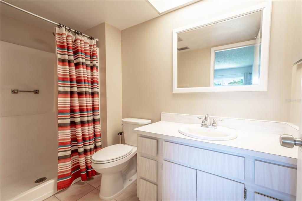 The primary bath features a walk-in shower, a mirrored vanity with storage and a ceramic tile floor.