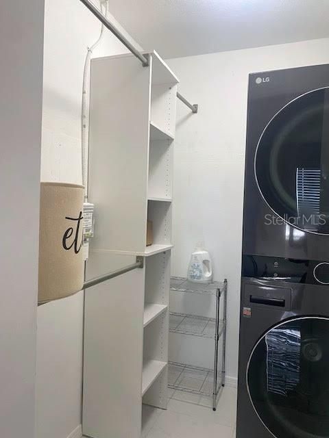 Primary Bedroom walk-in closet with stackable front loading washer/dryer