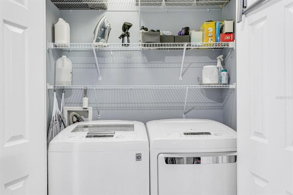 The laundry closet is complete with large size washer, dryer and shelving to keep things organized.