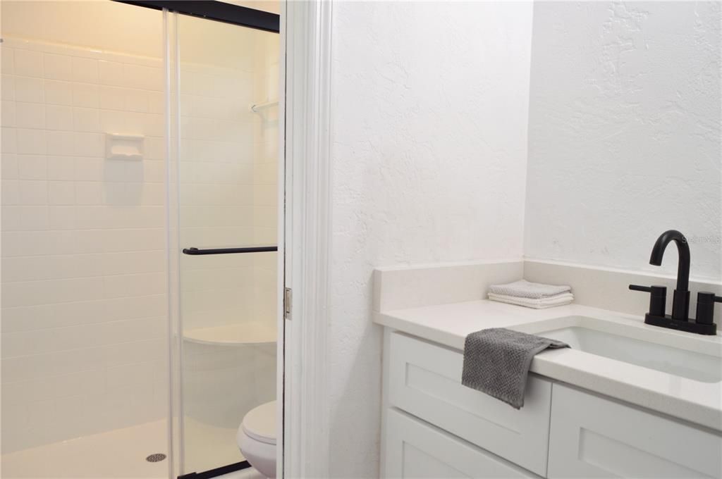 Enclosed Bathroom with shower stall and outside vanity