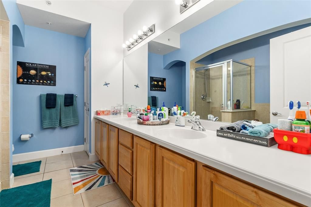 The luxurious bathroom boasts a large double vanity, stone countertop, garden tub, and walk-in shower