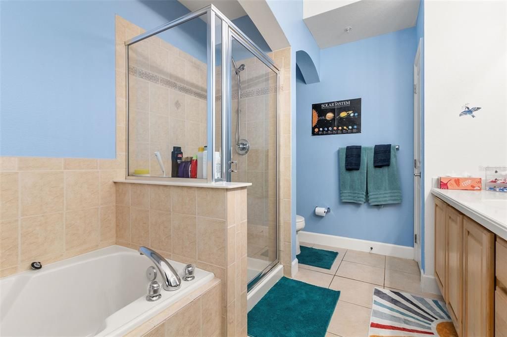 The luxurious bathroom boasts a large double vanity, stone countertop, garden tub, and walk-in shower