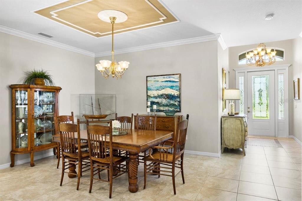 Spacious great room featuring 16" tile, 10' tray ceilings, custom built-ins, and a 4 panel sliding glass door that leads out to the screened-in lanai and heated pool.