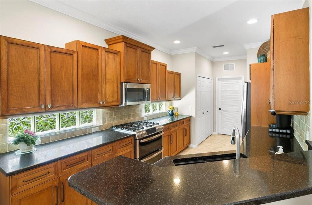 Large galley kitchen with solid wood cabinets, stainless steel appliances, a breakfast bar, dinette, and large pantry.