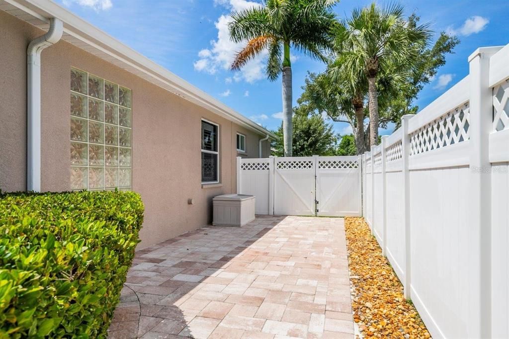 Screened-in Covered lanai featuring a solar heated pool, a sitting area, and an extended paver walkway/storage area.