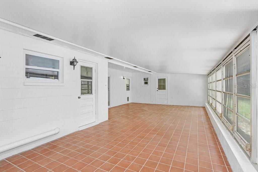 Enclosed sunroom/porch has sliders to the Family Room, a door to the Kitchen and a door leading into the Laundry Room.