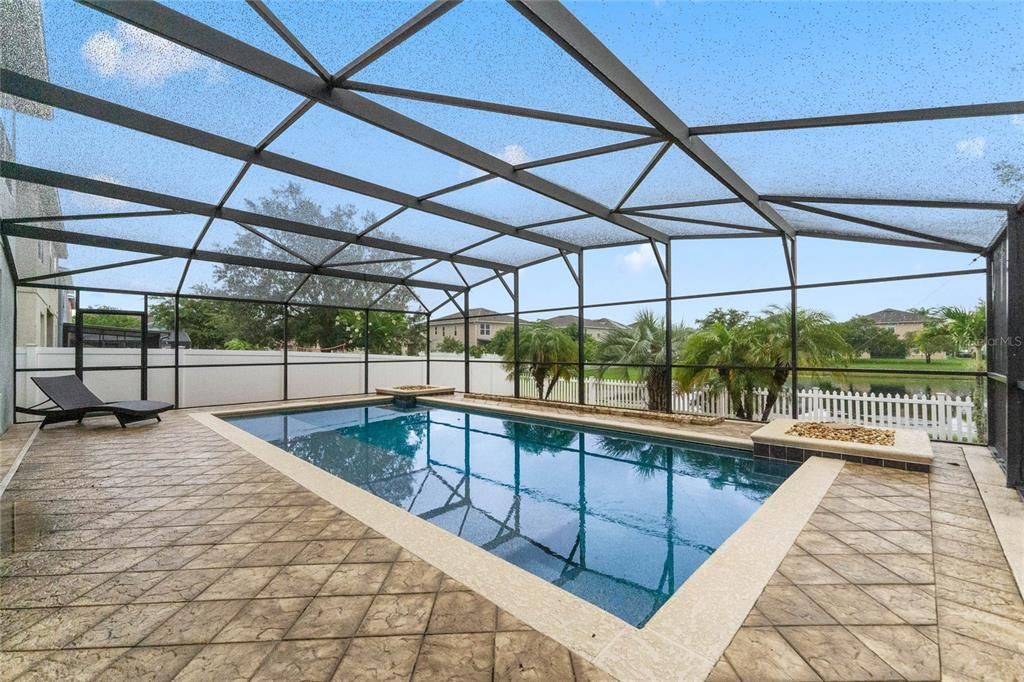 Beautiful Pool with upgraded tile decking. Planters in background. Pickett Fence for pond view.