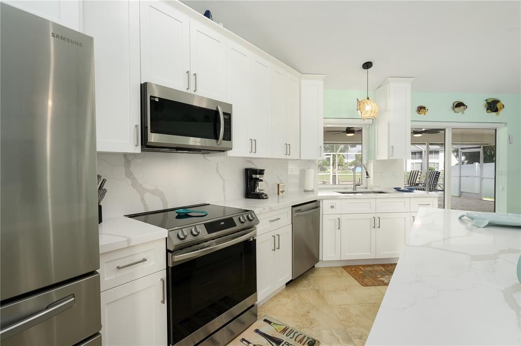 Kitchen with backsplash, sink, light tile flooring, and appliances with stainless steel finishes