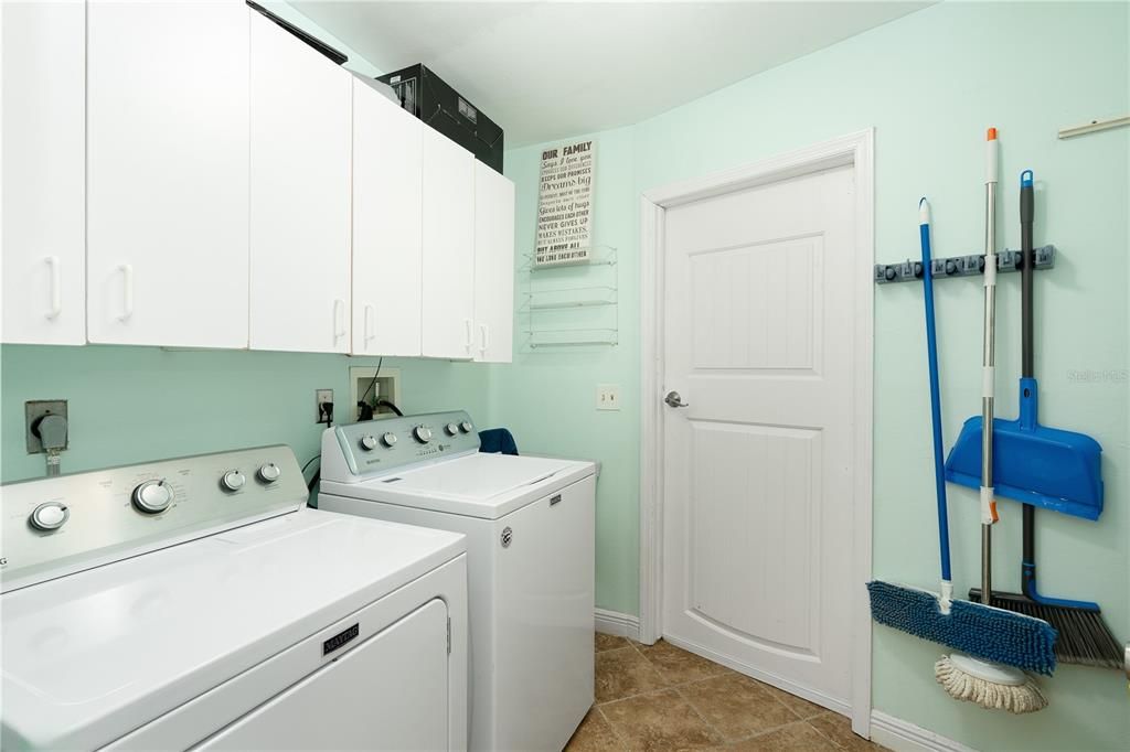 Laundry room featuring washer and dryer, cabinets, hookup for a washing machine, electric dryer hookup, and light tile floors