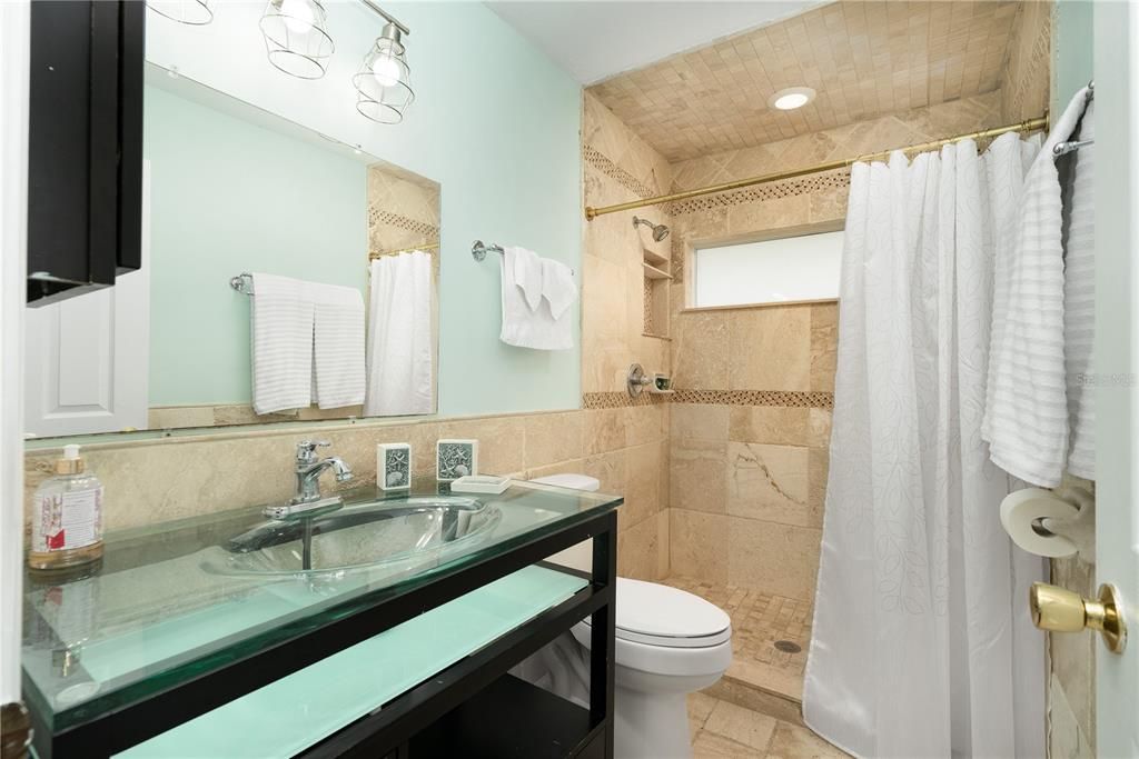 Bathroom with tile walls, toilet, tile floors, curtained shower, and vanity