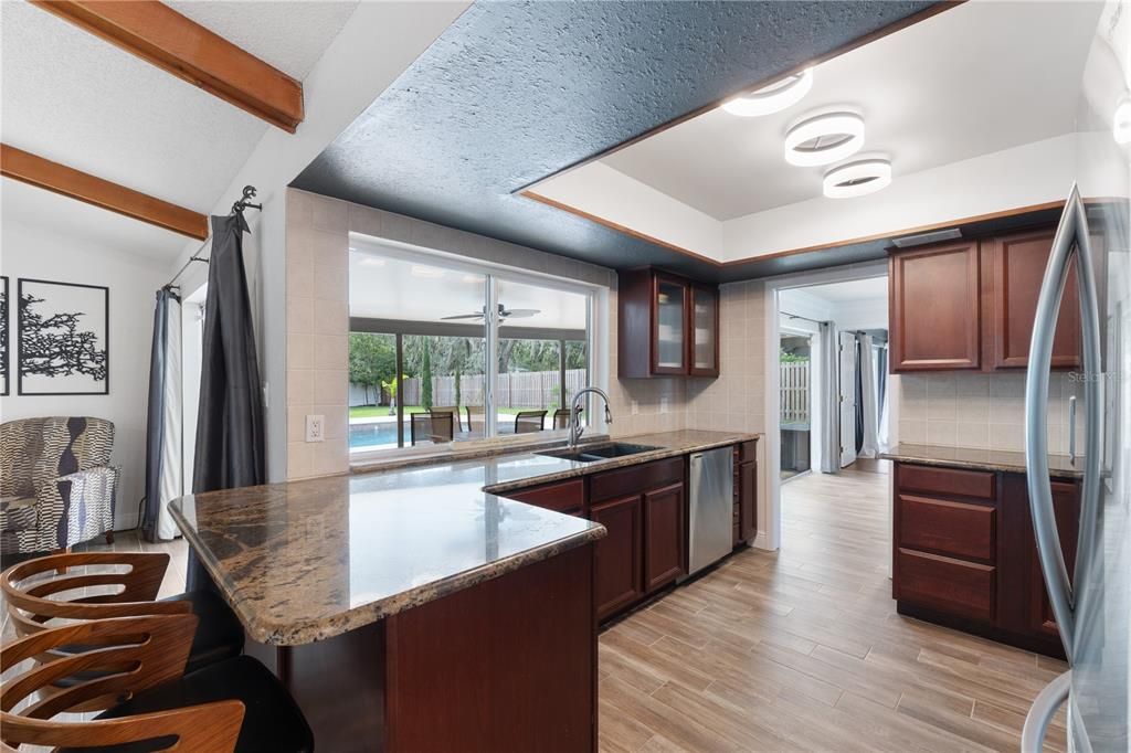 Window right over the kitchen sink keeping this kitchen full of light with nature & pool views!