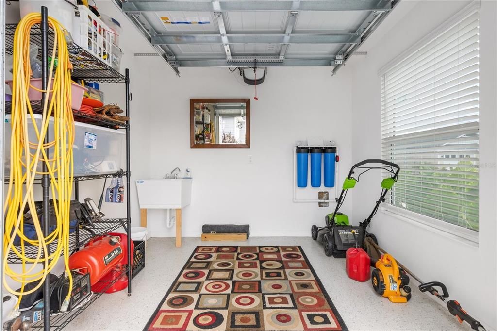 GOLF CART GARAGE WITH UTILITY SINK & NOVA WATER FILTRATION SYSTEM.  LAWN EQUIPMENT ON THE RIGHT STAYS - ALL ON LEFT IS NOT INCLUDED