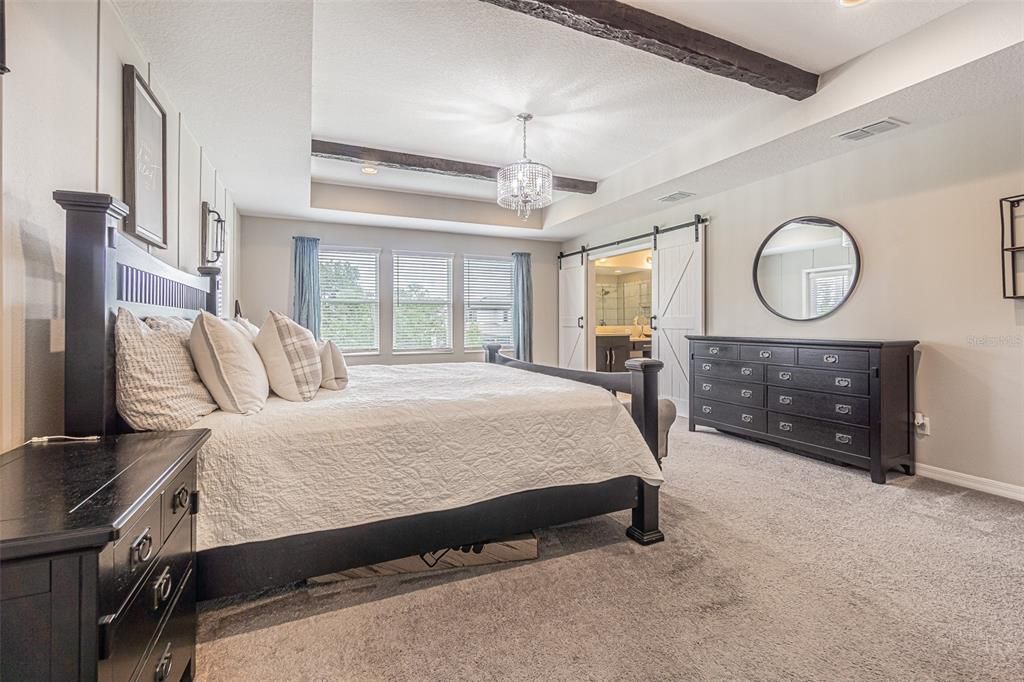 Gorgeous owner's retreat with tray ceiling, exposed beams, barndoors to ensuite bath. Private balcony is at the left rear corner