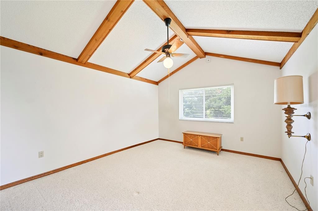 3rd bedroom with vaulted ceilings, beams, sliding door access to the enclosed porch