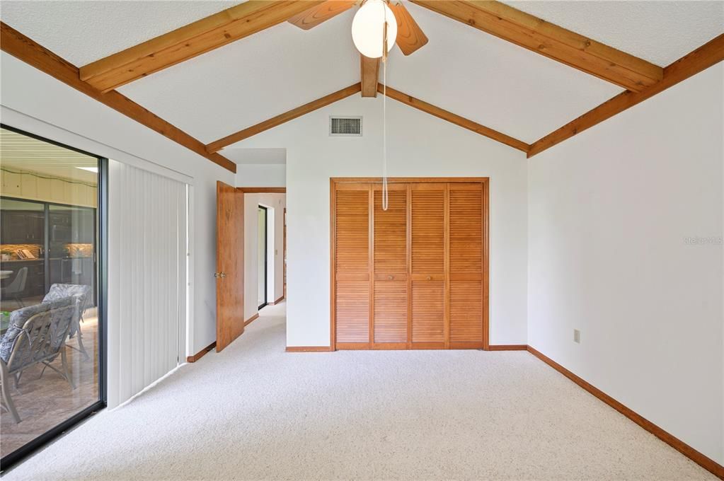 3rd bedroom with vaulted ceilings, beams, sliding door access to the enclosed porch