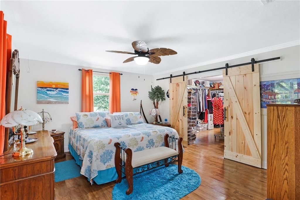 A cheerful primary bedroom with barn doors into the incredible closet loaded with shelves and space to stay organized!