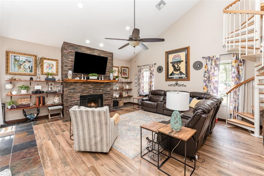 Oversized family room with vaulted ceilings and a cozy floor-to-ceiling stone fireplace with custom wood shelving.