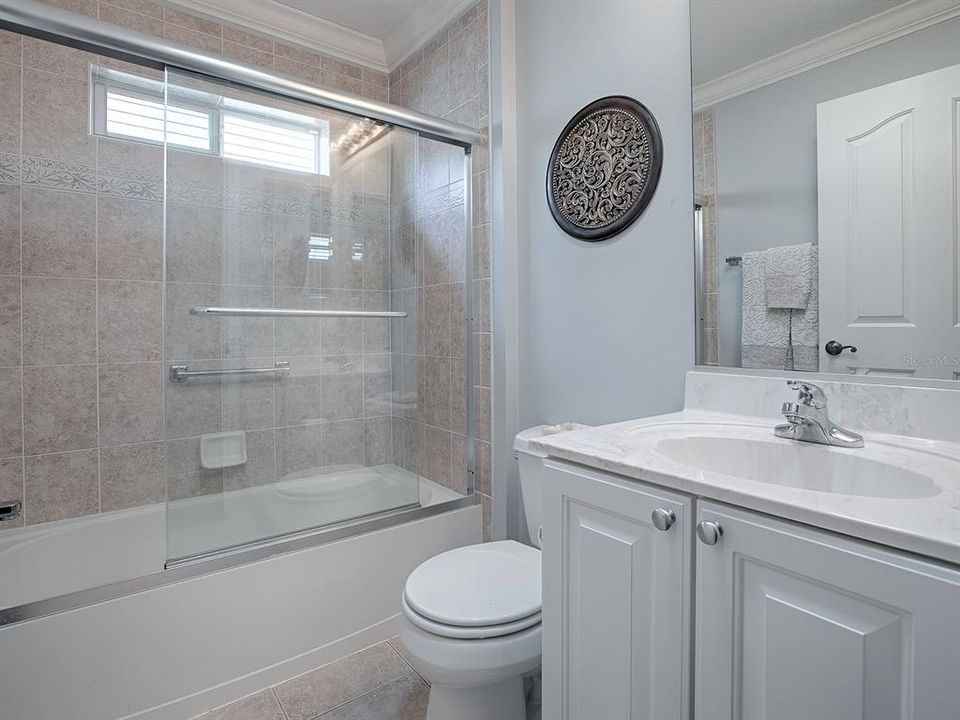 GUEST BATH WITH TUB/SHOWER AND GLASS ENCLOSURE.