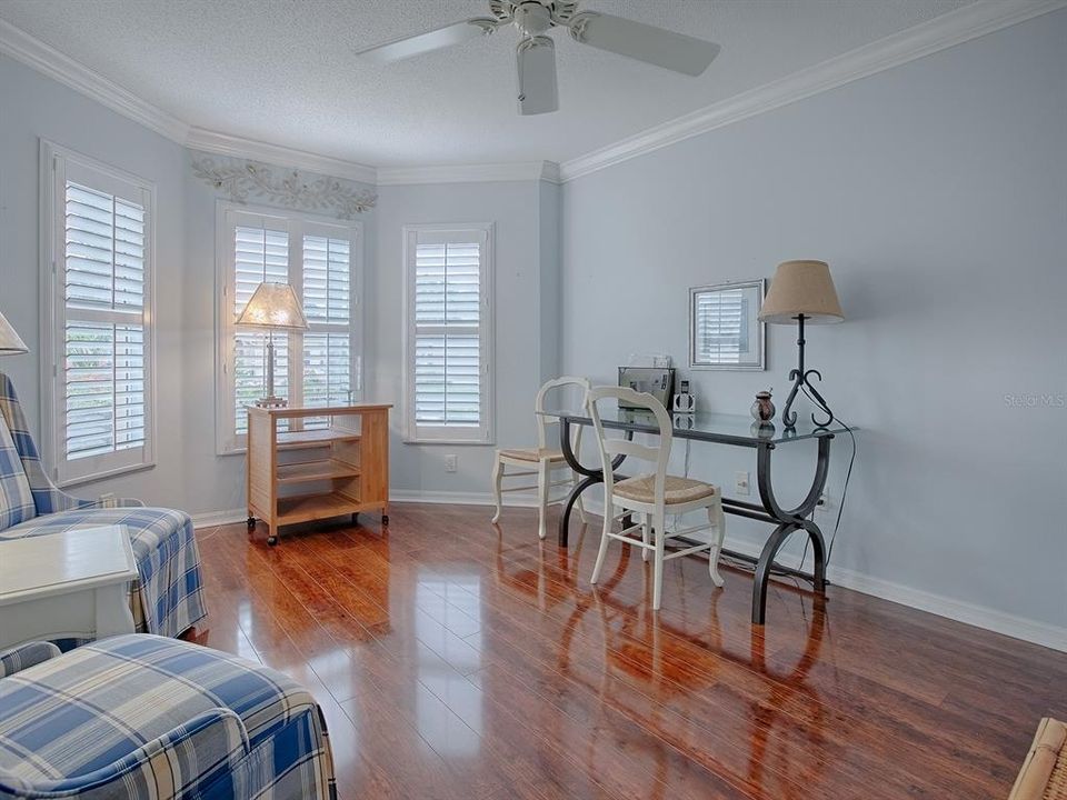 ON THE OPPOSITE SIDE OF THE HOME IS THE GUEST SUITE. THIS IS THE FRONT GUEST ROOM WITH BAY WINDOW, PLANTATION SHUTTERS BEING USED AS A SITTING ROOM AND OFFICE.