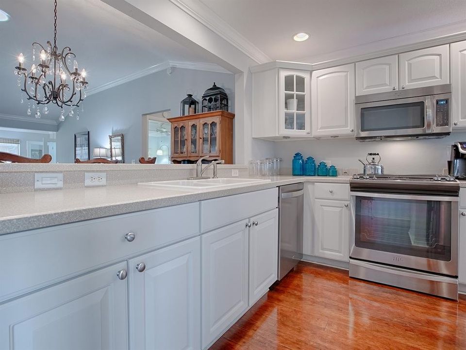 TO THE RIGHT IS YOUR SPACIOUS EAT-IN KITCHEN WITH CORIAN COUNTERTOPS, WHITE CABINETRY WITH OVER AND UNDER CABINET LIGHTING AND PULL OUT DRAWERS IN LOWER CABINETS.