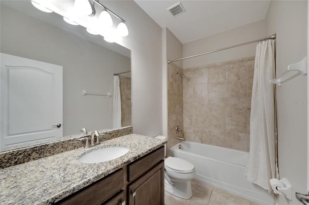 Full bathroom with upgraded Counter-Height Cabinetry, extra-long Granite countertop, and tub/shower combo.