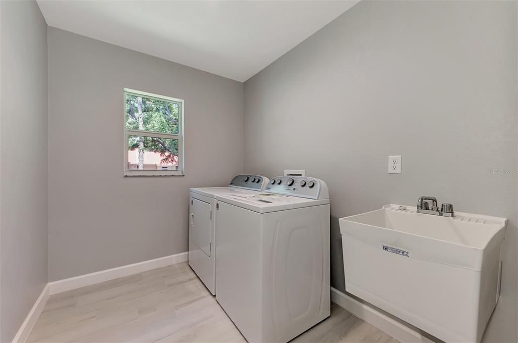 Inside laundry room is quite roomy and offers washer/dryer and wet sink.  Pleny of space to add storage cabinetry.