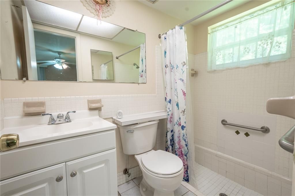 The ensuite bath features a step down shower, ceramic tile flooring and a mirrored vanity with storage.