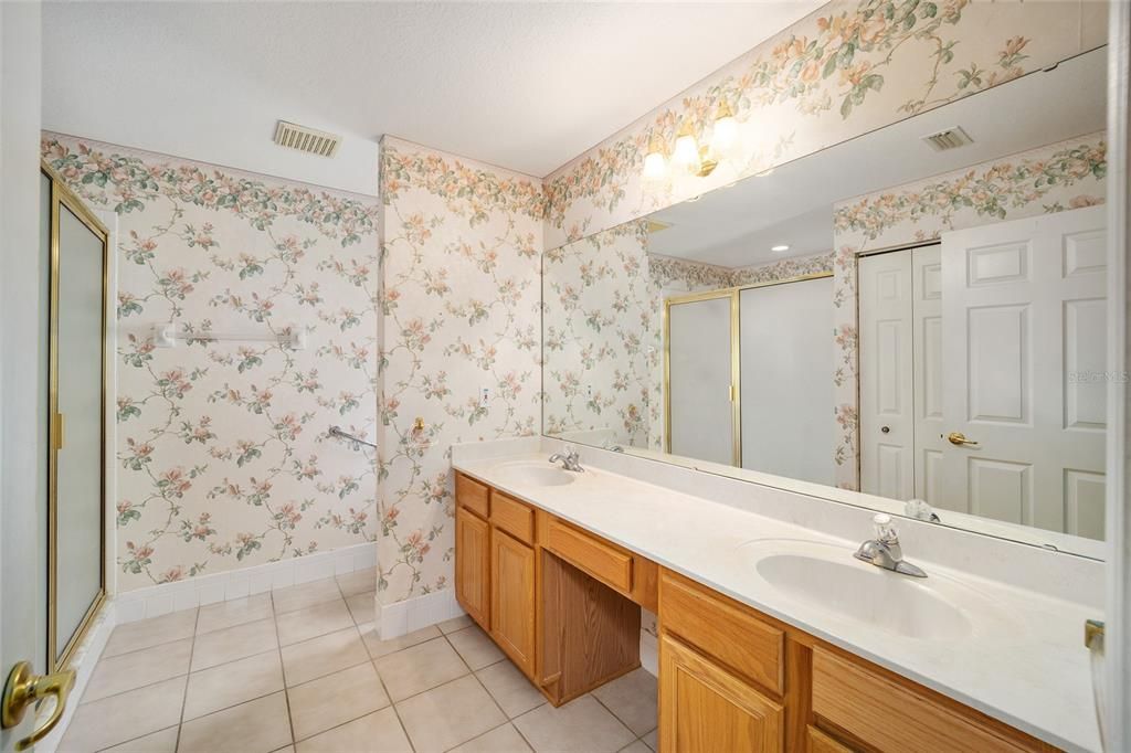 Bath has long double vanity with knee space for makeup area, and generous linen closet