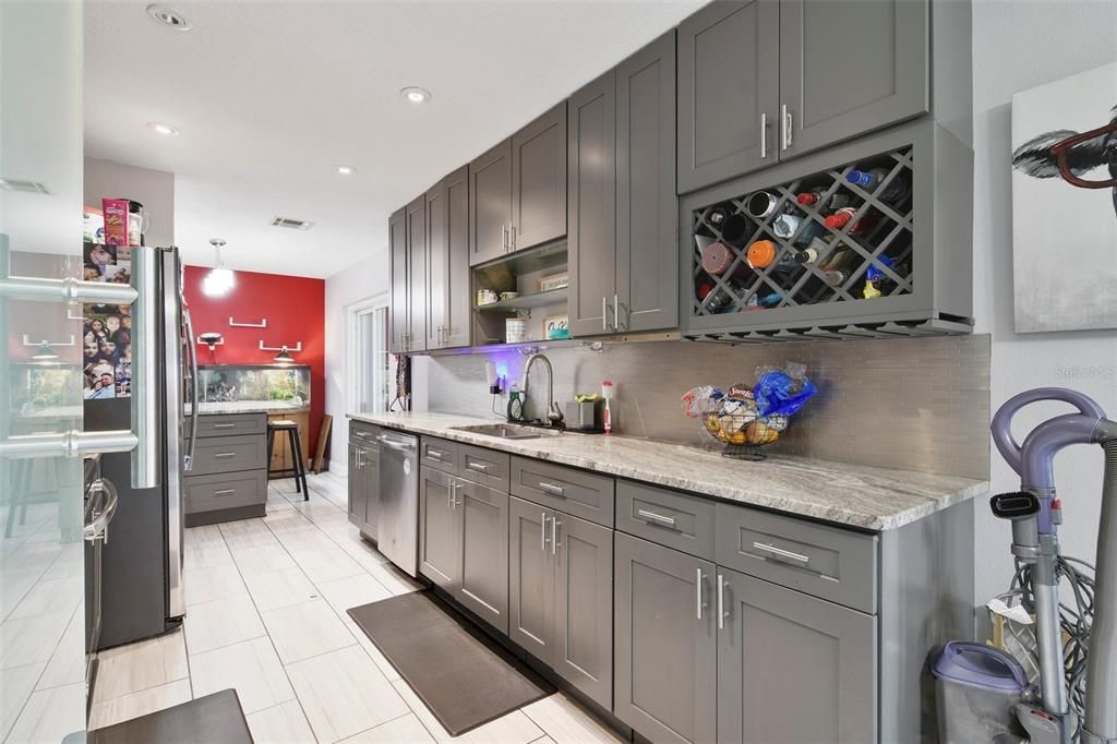 The galley style kitchen has been renovated to include modern cabinetry, STAINLESS STEEL APPLIANCES, stone counters, tiled backsplash, pantry storage and a casual eat-in space with sliding glass door access to the ENCLOSED LANAI.