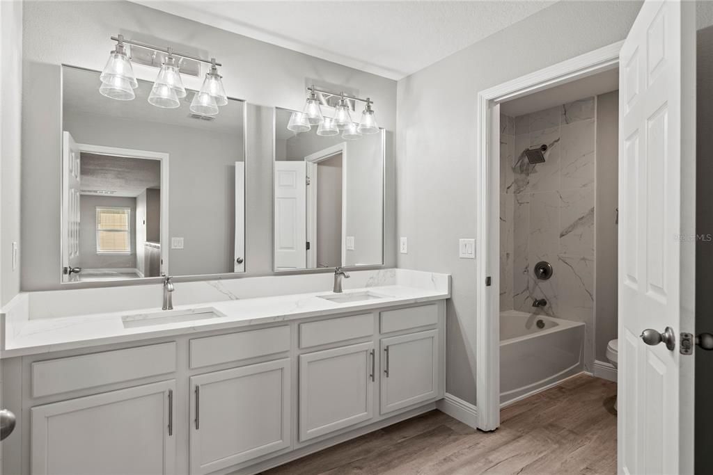 Upstairs Hall Bath with double quartz topped vanity, marble tiled shower/tub combo and all new finishes