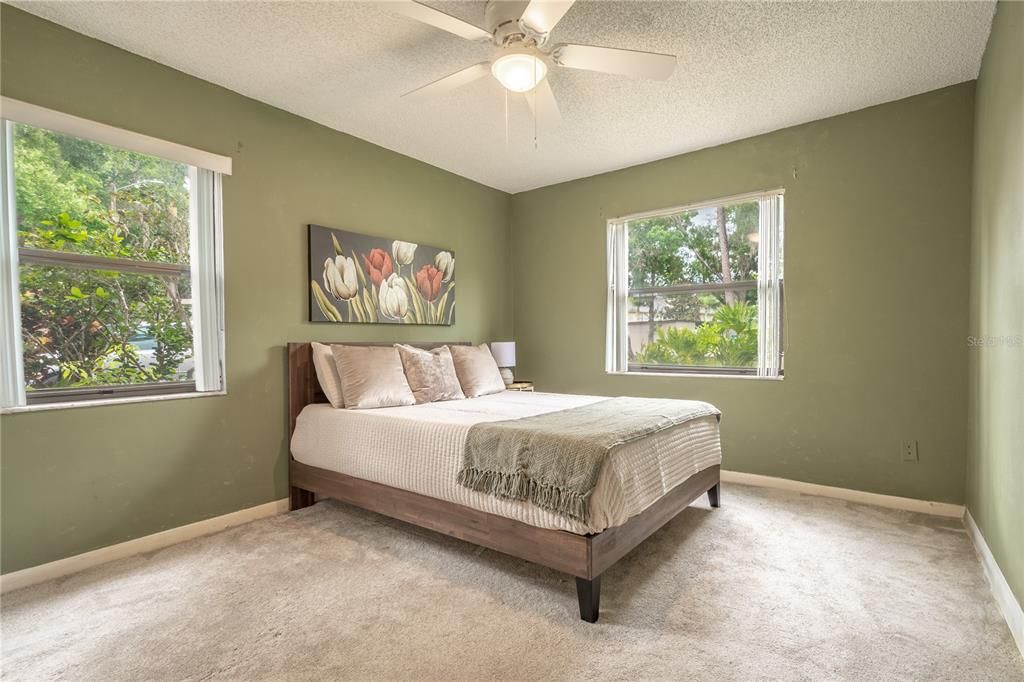 Bedroom 2 features neutral tone carpet and a ceiling fan with light kit.