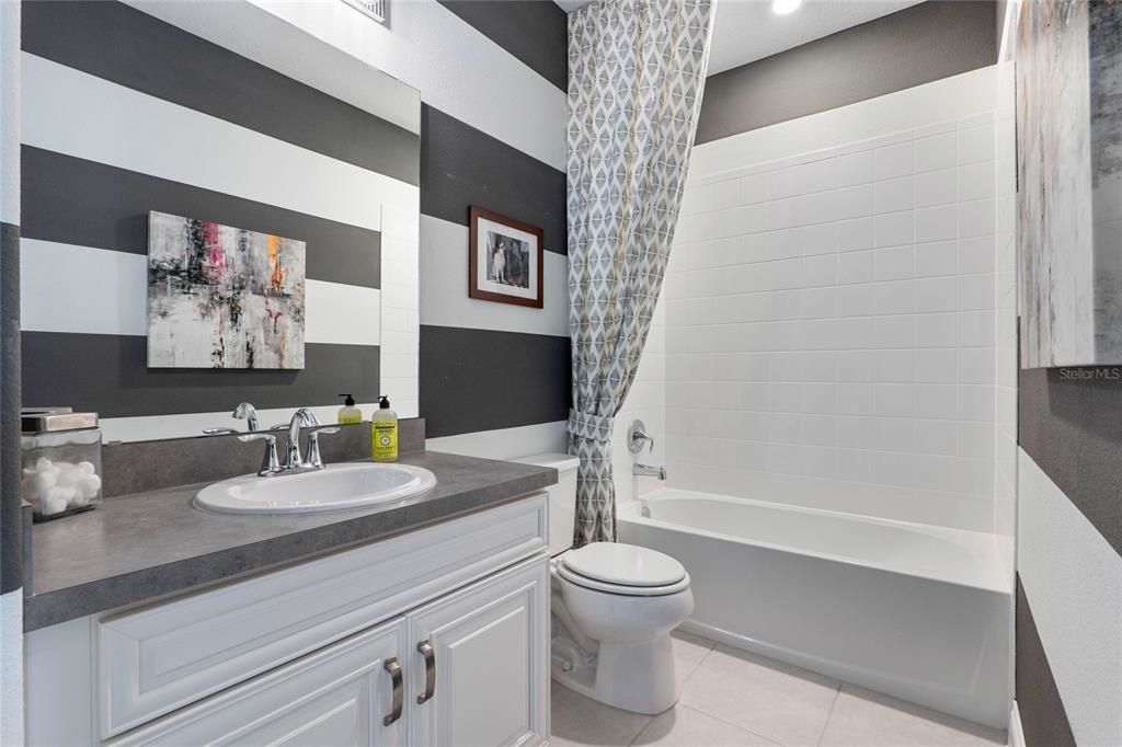 other bathroom with single sink vanity area, tub and shower