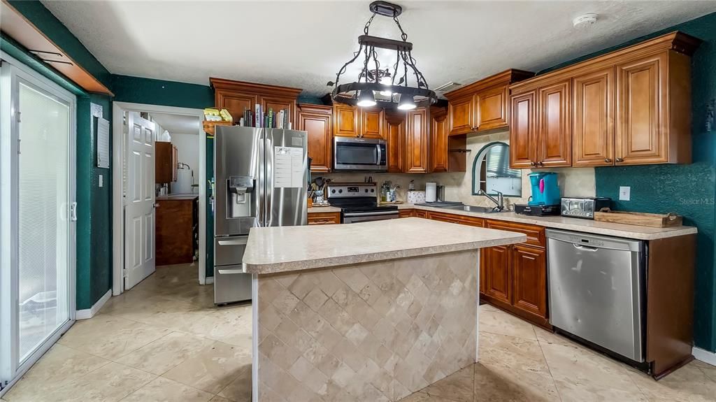 Thru the sliding glass doors on the left, you will find the screened back porch.  Straight thru the kitchen leads you to the laundry room and Converted 4th Bedroom