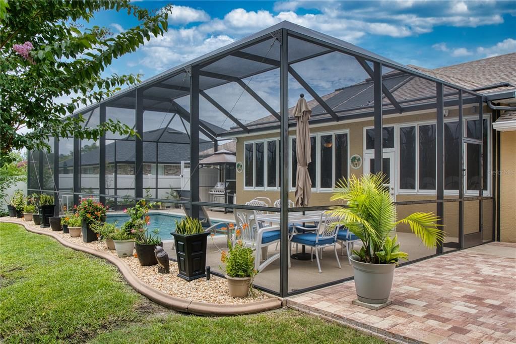 Beautiful concrete curbing around the pool cage with river rock stone infill, adding an elegant touch to the outdoor space.