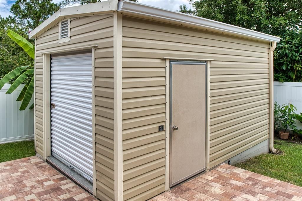 More than just a shed, this well-built storage building features a roll-up garage door, a side pedestrian door, and its own gutters, providing ample space and functionality.