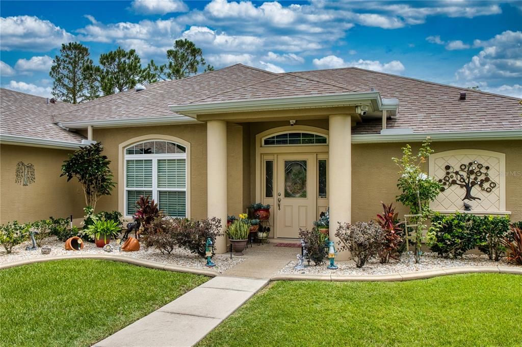 Stunning front entryway featuring coved, round columns and a front door flanked by two elegant leaded glass panels.