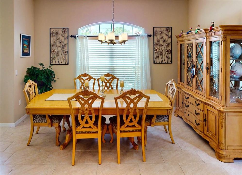 Formal dining area with a large arched window, perfect for elegant gatherings and enjoying natural light.